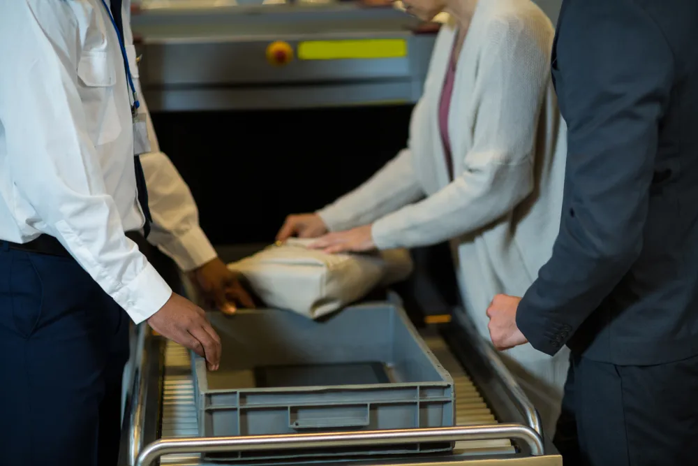 Kontrollbeamter prüft die Tasche eines Reisenden am Flughafen